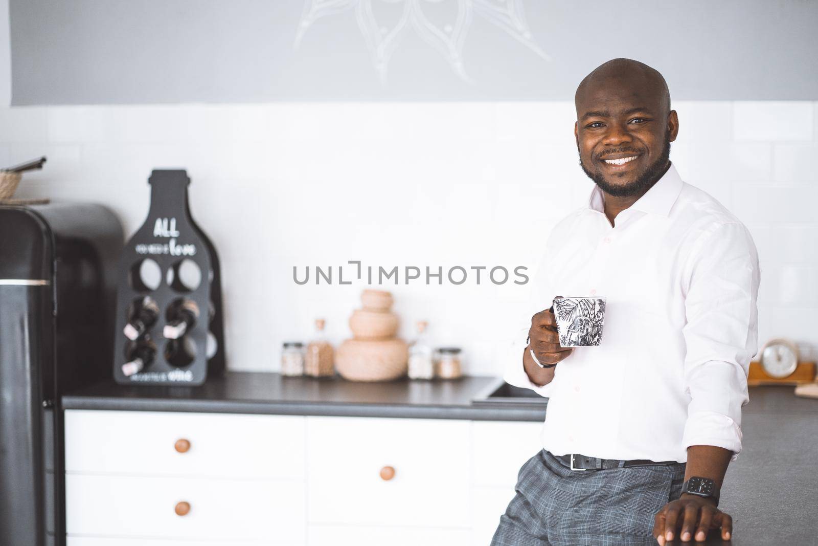 Successful Young Businessman. African American Guy Smiling In Kitchen With A Cup In Hand. Rich Investor In His Home Before Work. Concept Of Victory, Personal Growth. High Quality Photo