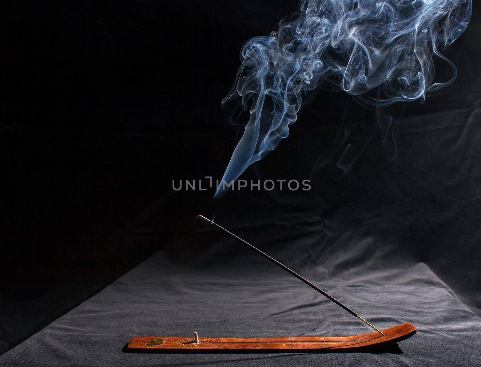 indian incense stick with smoke on black background indoor closeup