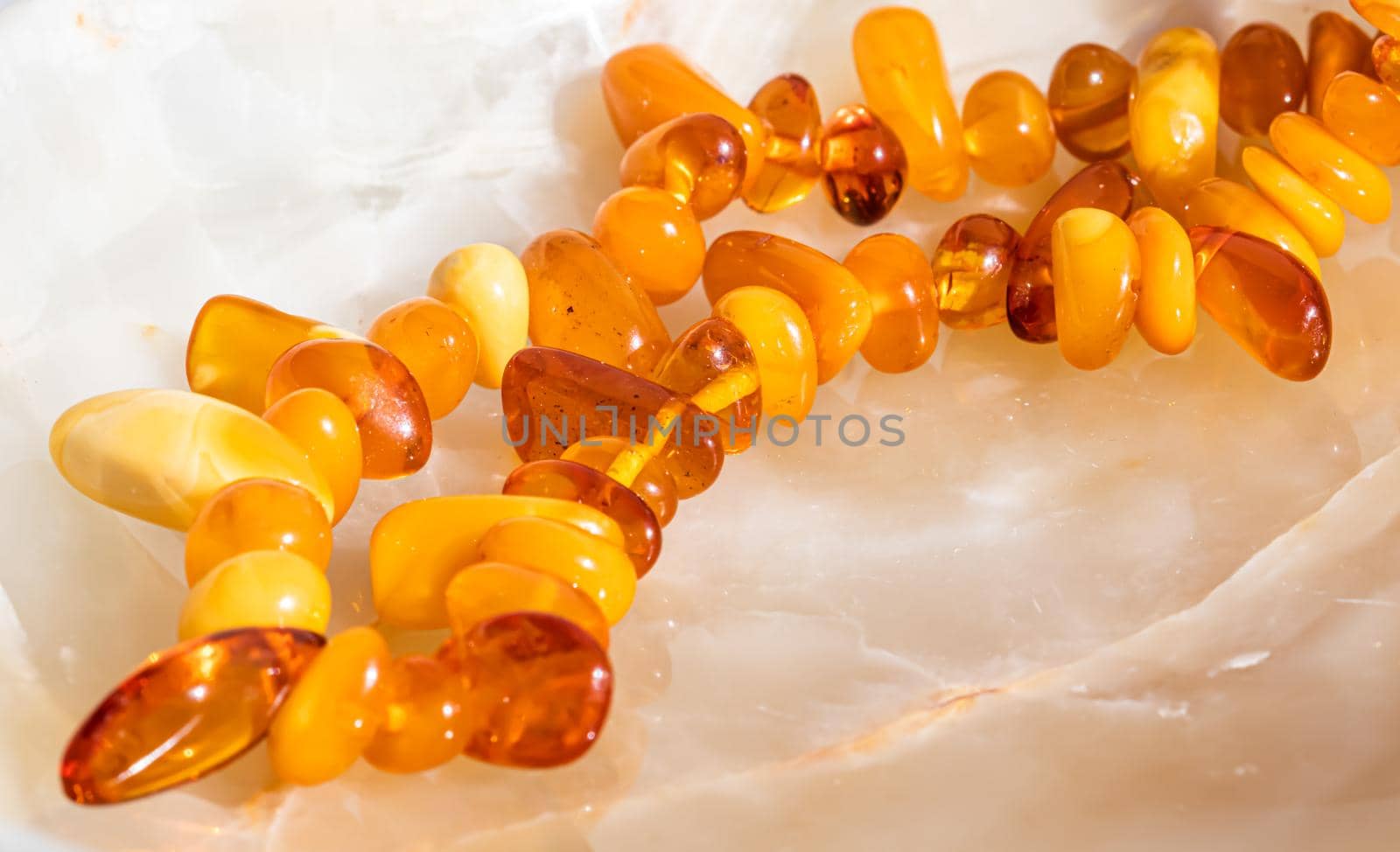 Solar beads of fiery amber on onyx marble background. Natural stone backdrop.