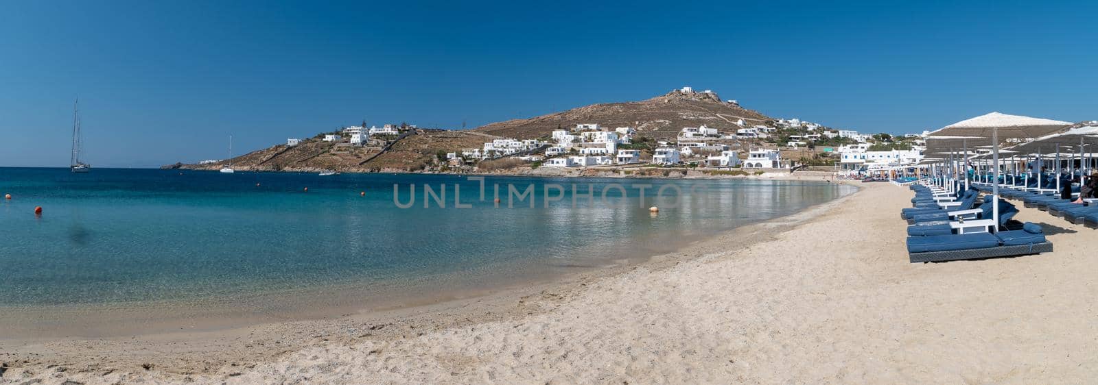 Ornos beach Mykonos island, famous Ornos beach organized with sun beds emerald clear water beach of Ornos in island of Mykonos, Cyclades, Greece. 
