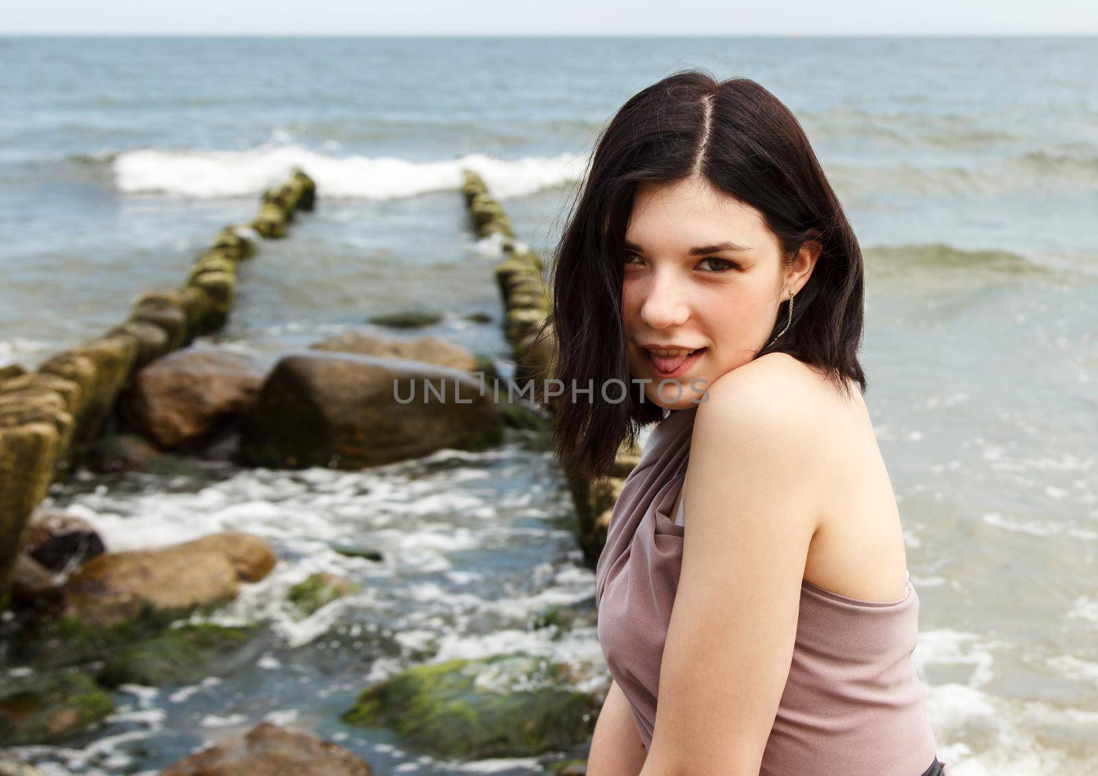 portrait of a young beautiful brunette woman by the sea on summer day