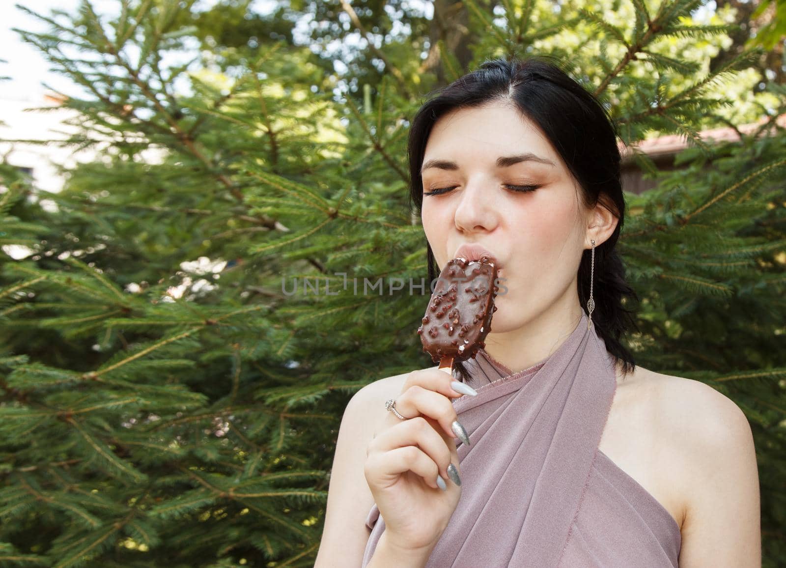 young brunette woman eating ice cream outdoor on summer day