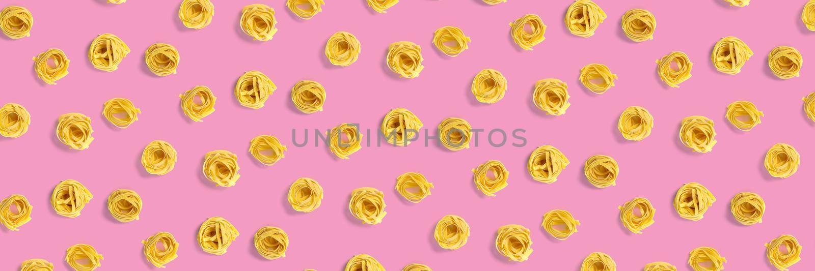 background from Italian tagliatelle pasta. raw pasta fettuccine, pop art background, flat lay. Italian raw nest pasta isolated on pink. not seamless pattern