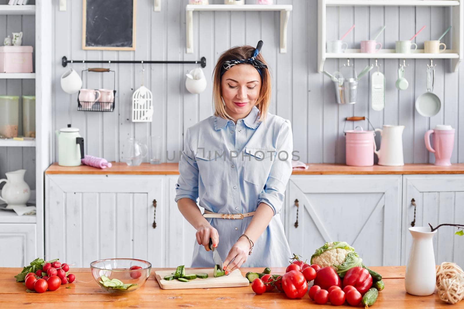 Beautiful young woman is preparing vegetable salad in the kitchen. Healthy Food. Cooking at home. Dieting Concept