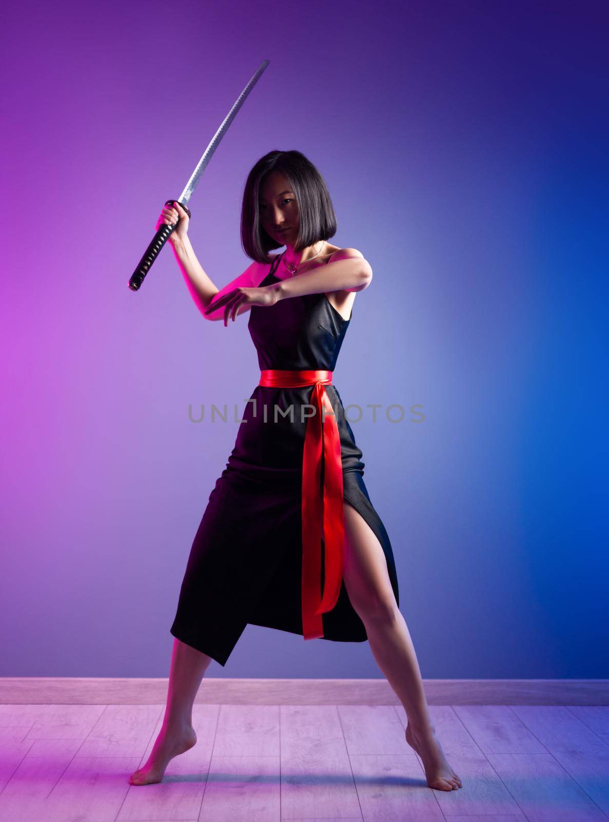 the slender Asian woman in a black dress with a katana in her hand image of a samurai on a neon background