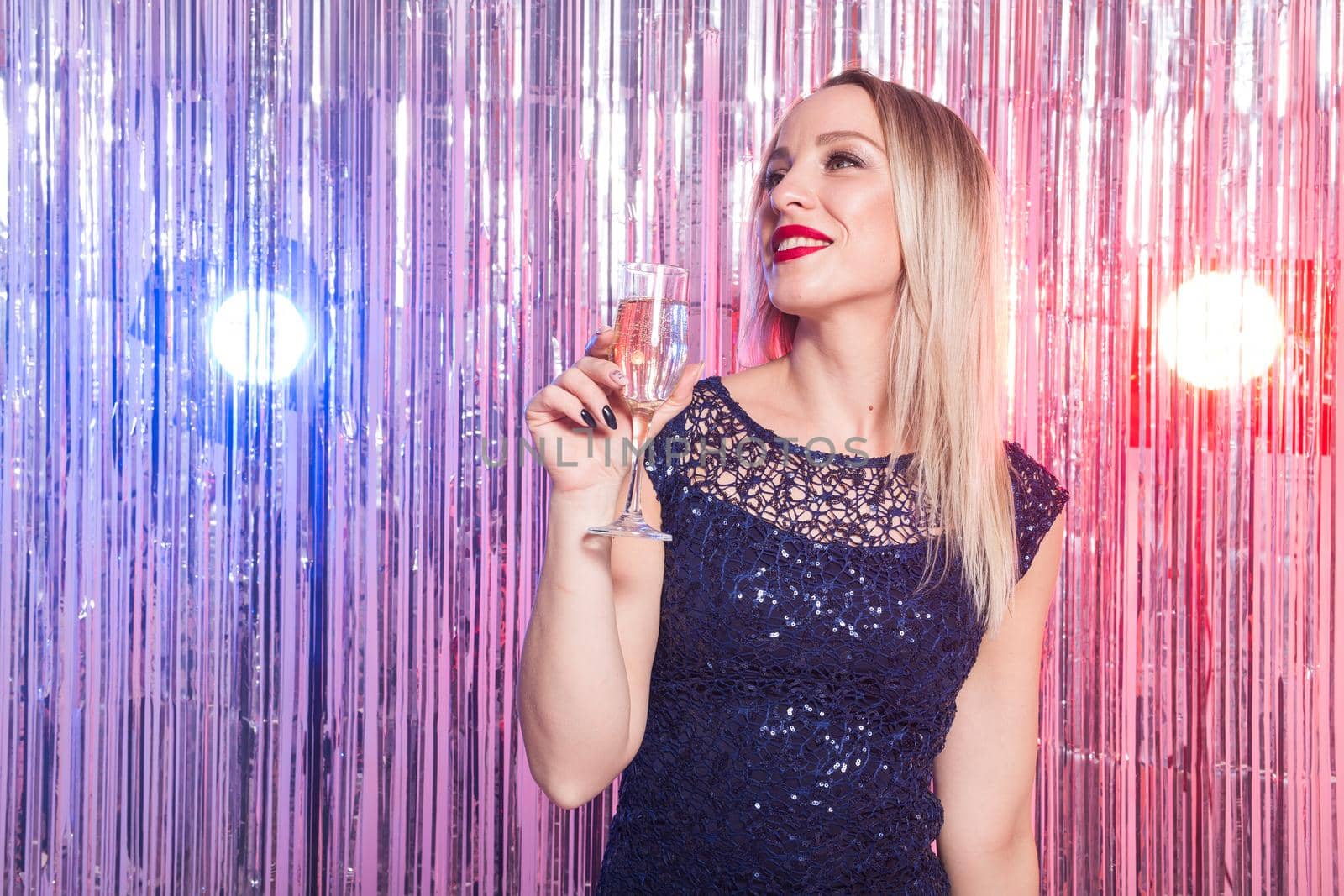 Party, drinks, holidays and celebration concept - smiling woman in evening dress with glass of sparkling wine over shiny background. by Satura86