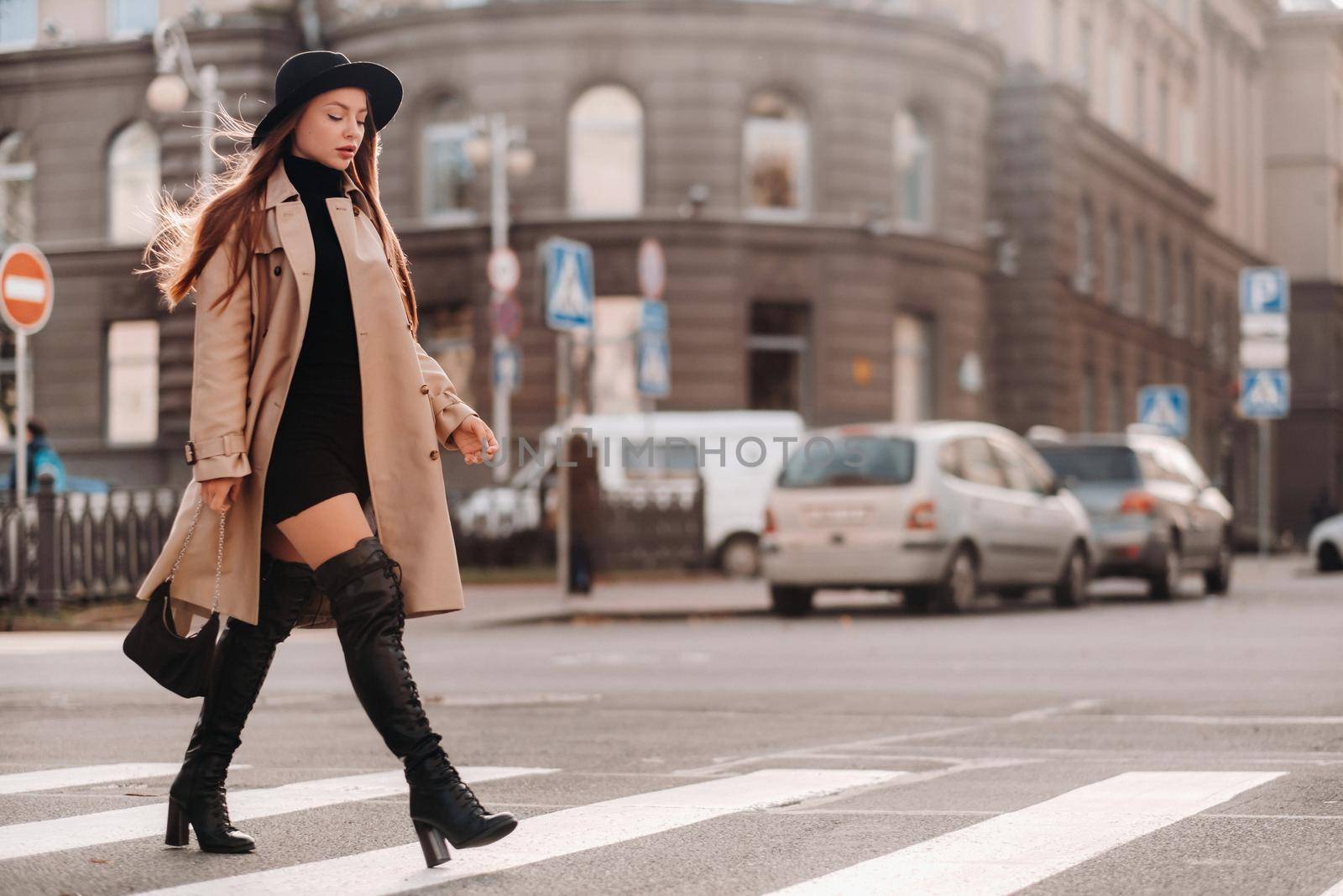 Stylish young woman in a beige coat in a black hat on a city street. Women's street fashion. Autumn clothing.Urban style.