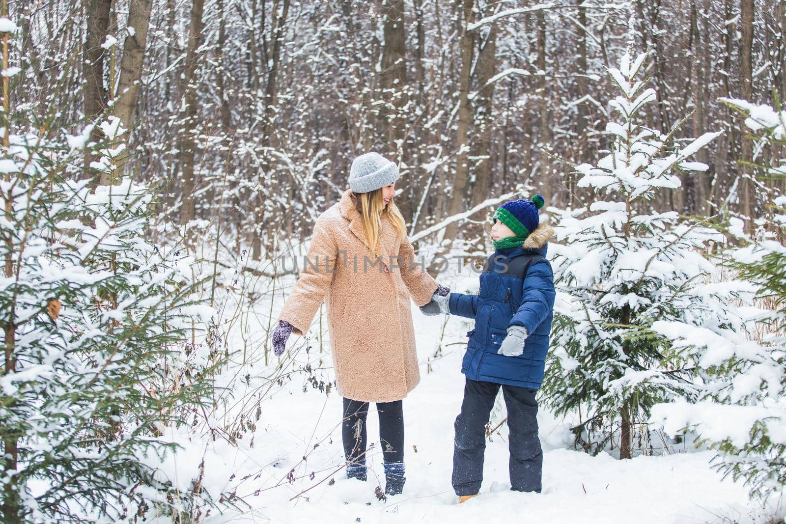 Fun and season concept - Happy mother and son having fun and playing with snow in winter forest by Satura86