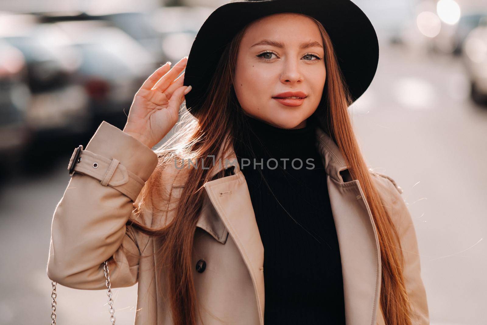 Stylish young woman in a beige coat in a black hat on a city street. Women's street fashion. Autumn clothing.Urban style.