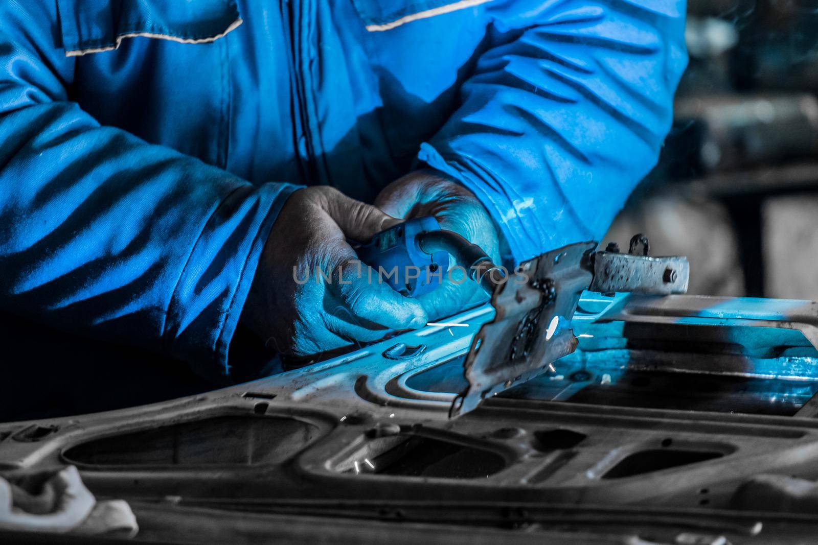 Close-up of the welding process. The hands of a man welder hold the welding and repair the car door on plant.