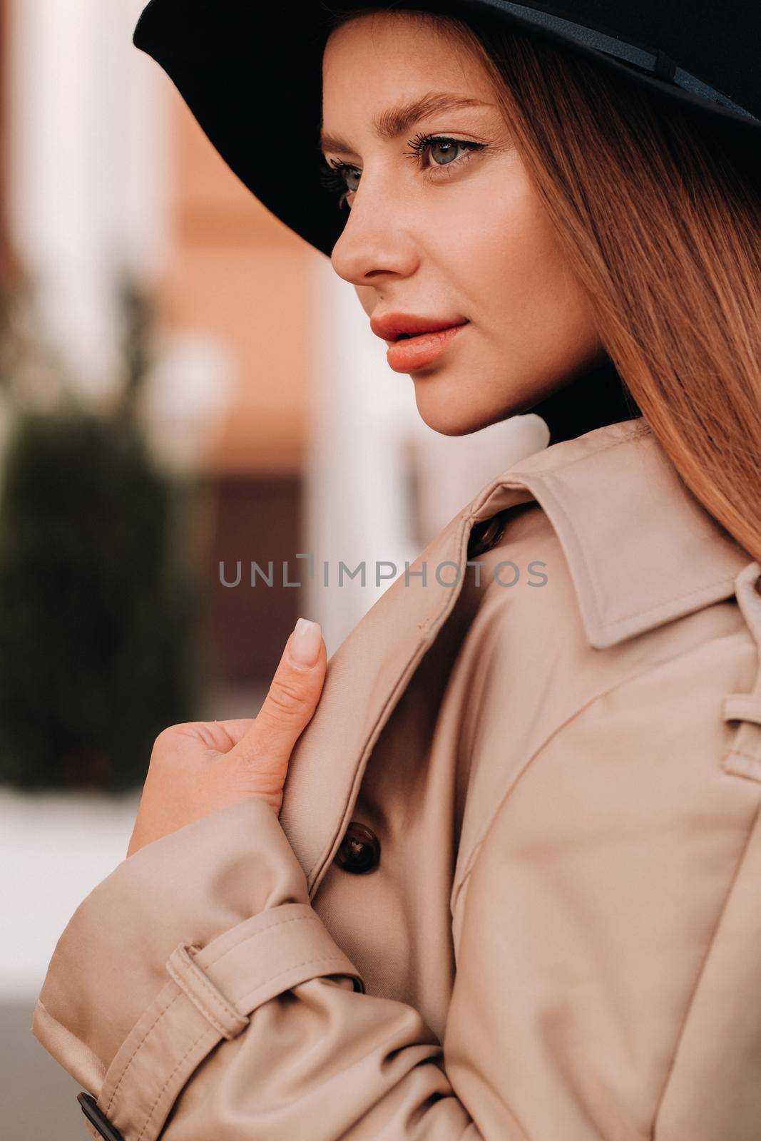 Portrait of a girl in a beige coat and black hat on a city street. Women's street fashion. Autumn clothing.Urban style.