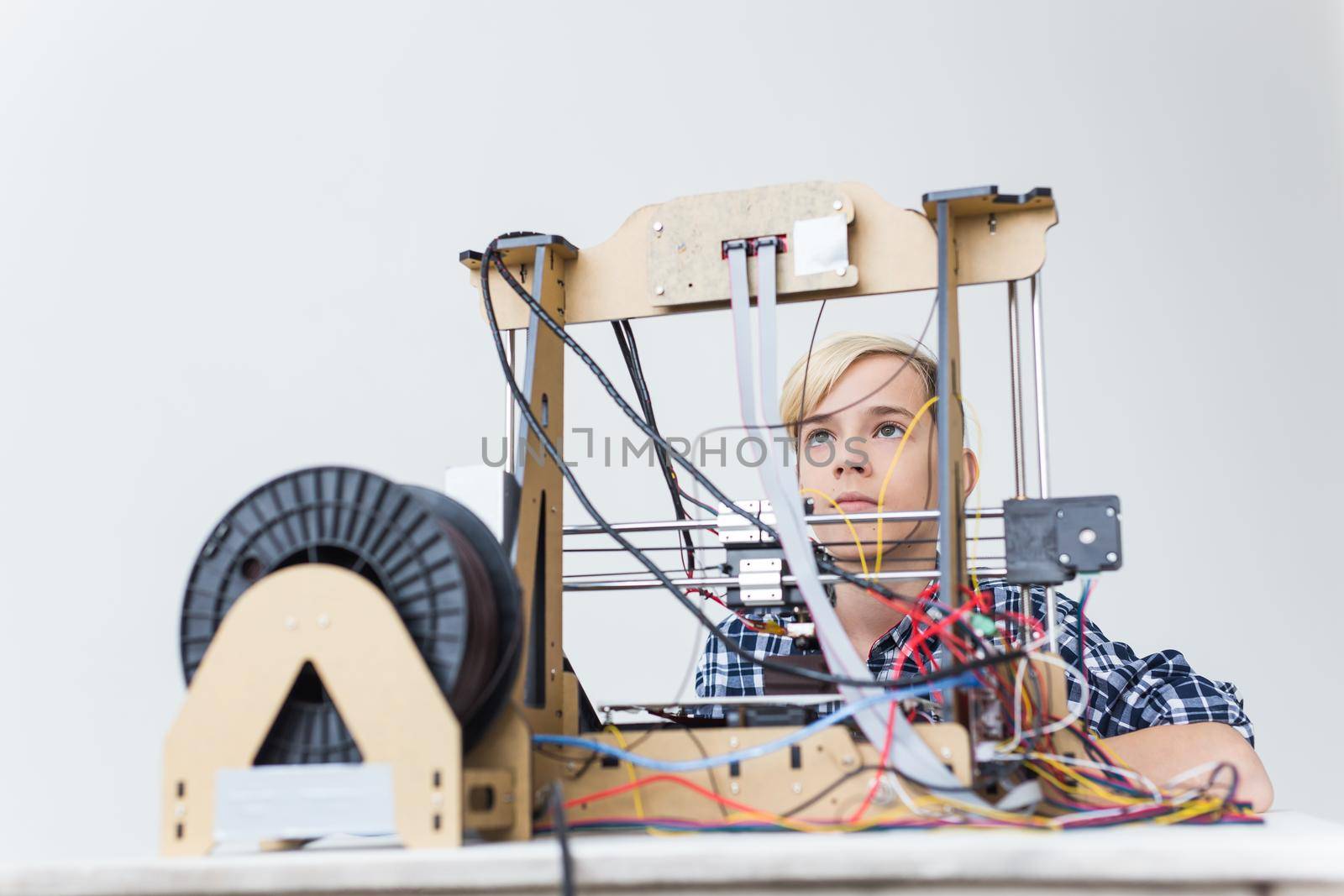 Education, children, technology concept - teen boy is printing on 3d printer