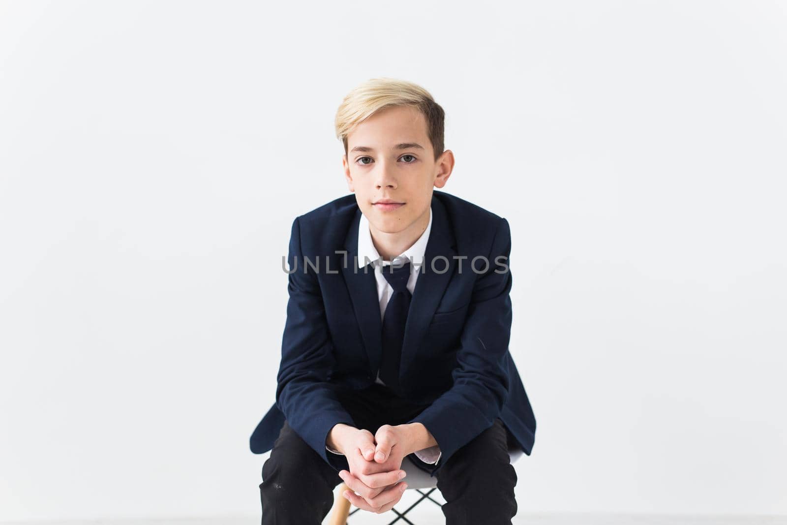 Portrait of stylish school boy teenager in white shirt and jacket against white background with copy space