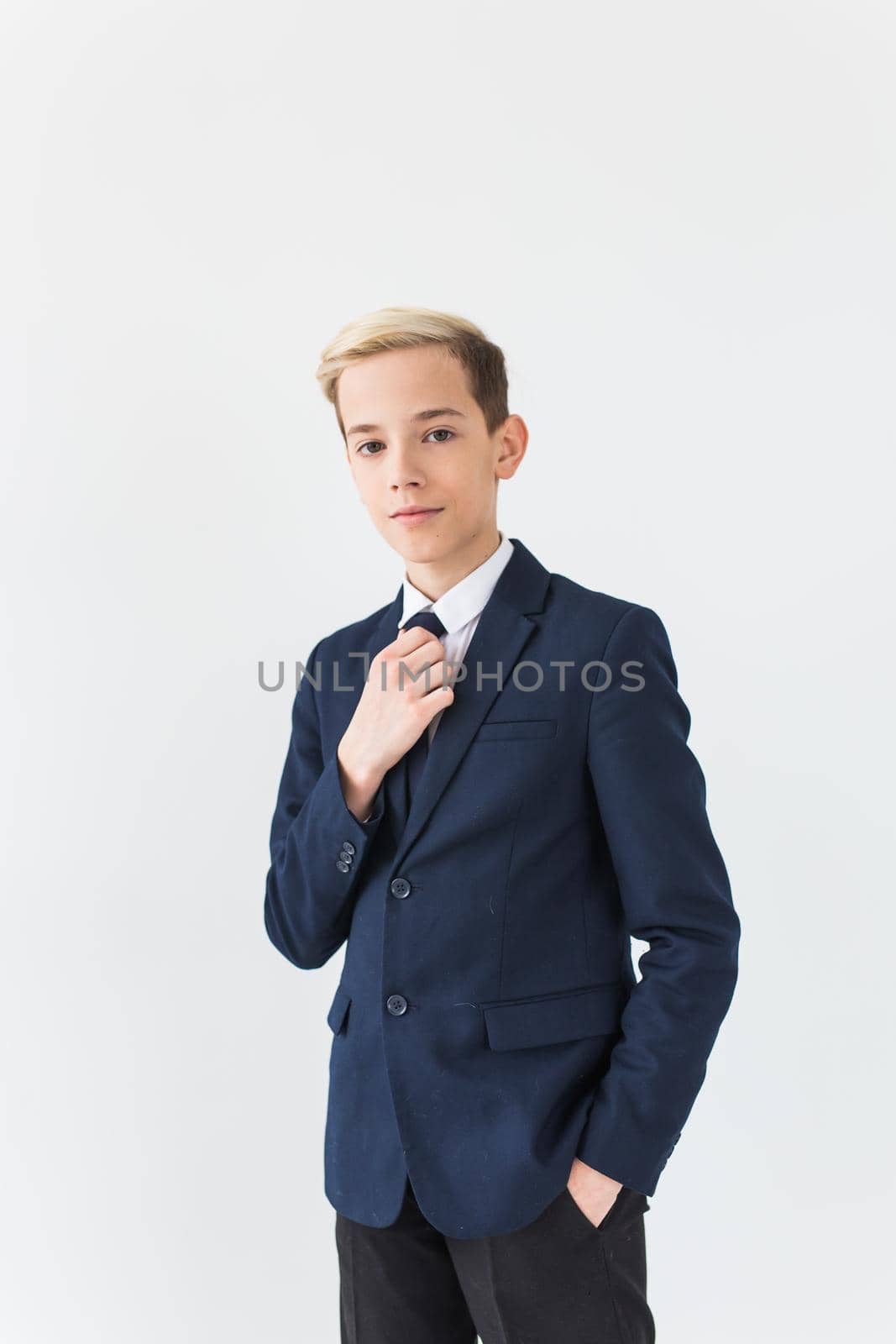 Portrait of stylish school boy teenager in white shirt and jacket against white background with copy space