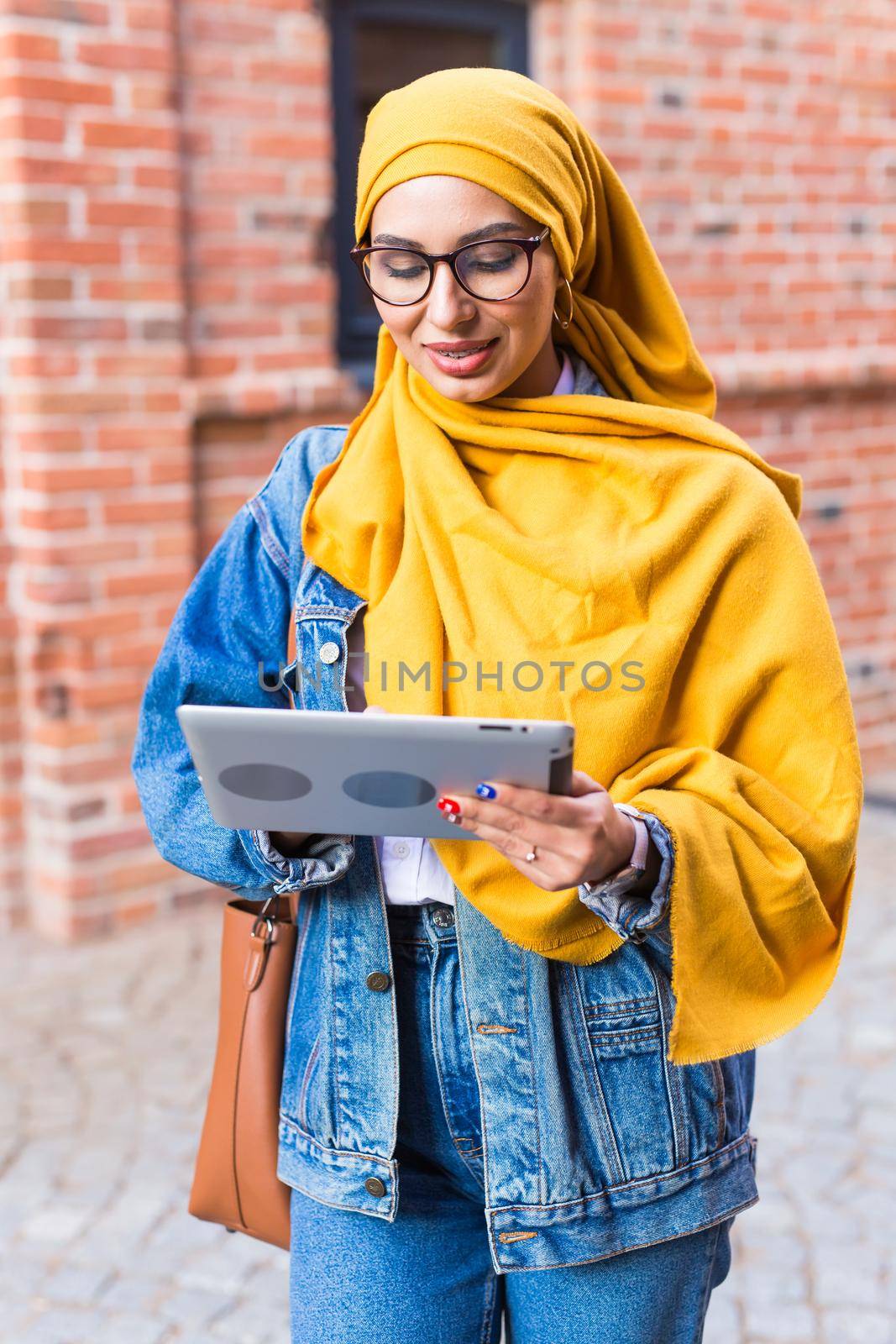 Arab woman student. Beautiful muslim female student wearing yellow hijab holding tablet