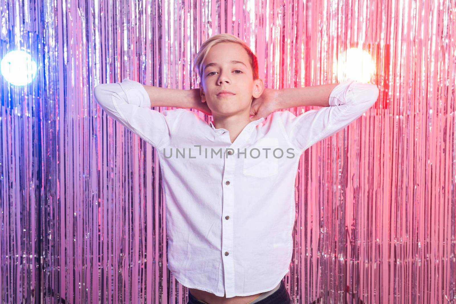 Awkward age and teenage concept - Portrait of teen boy at a party. Shiny background. by Satura86