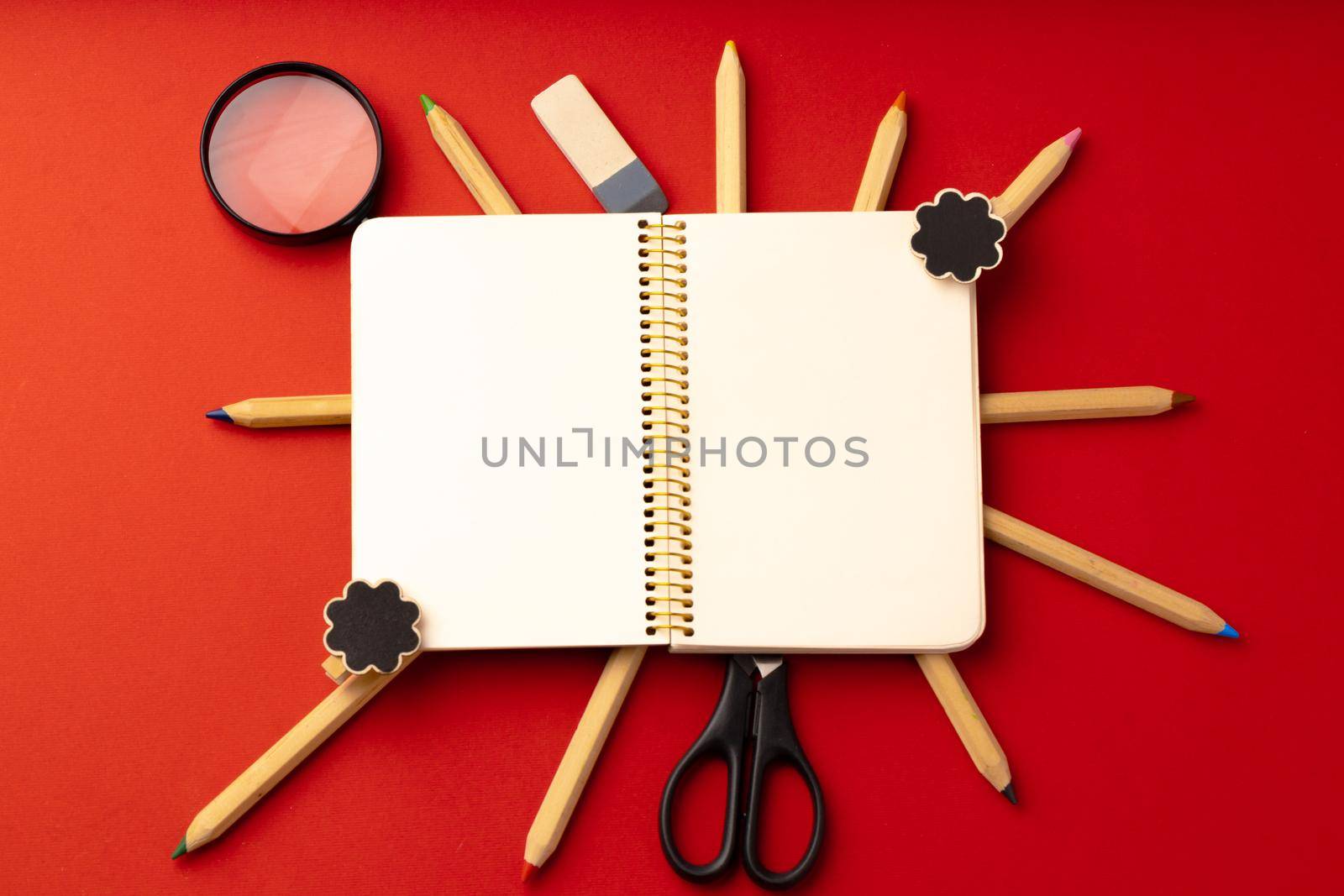 Open notepad and color pencils on paper background top view
