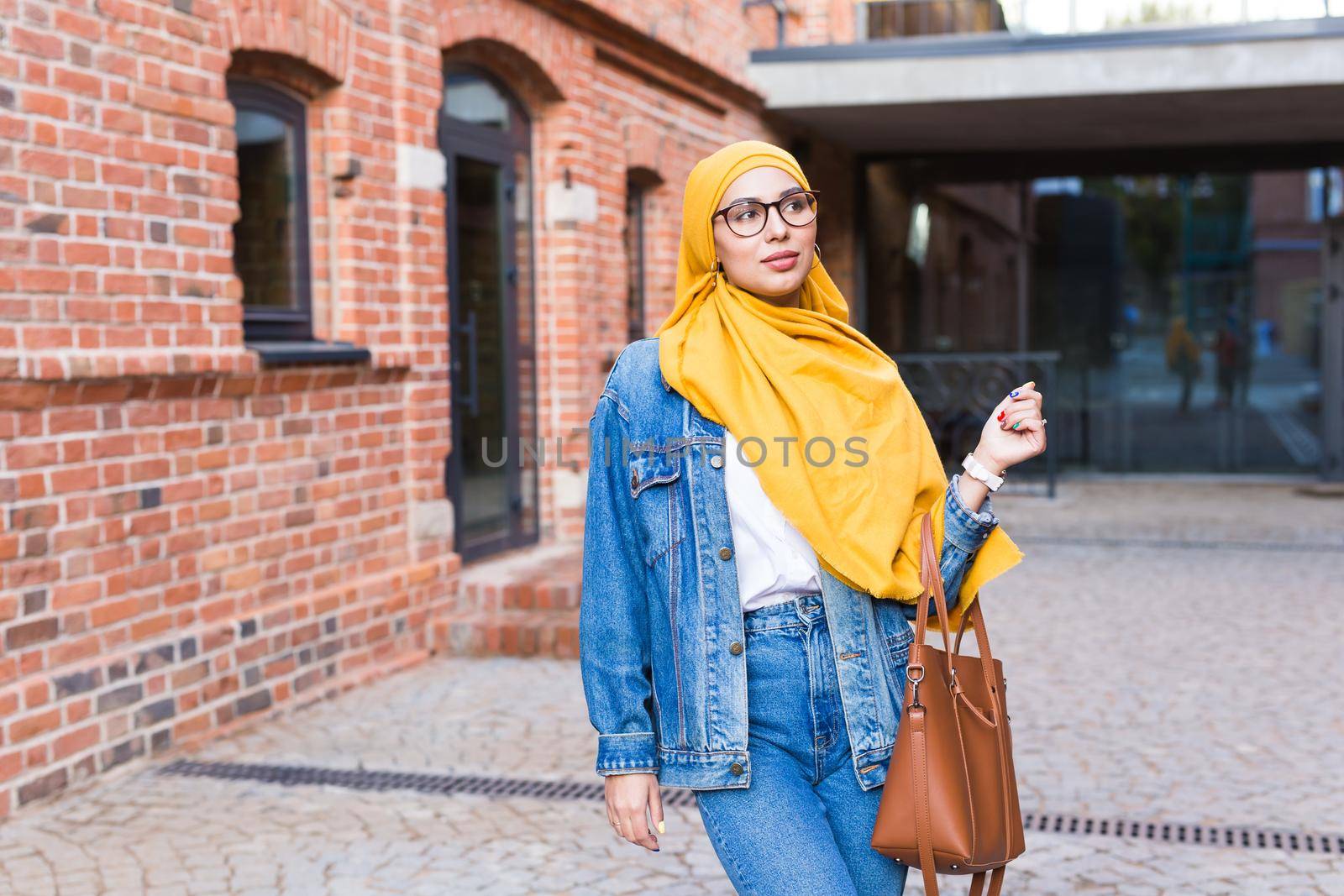 Beautiful Arabic muslim woman wearing yellow hijab, stylish female portrait over city street. by Satura86