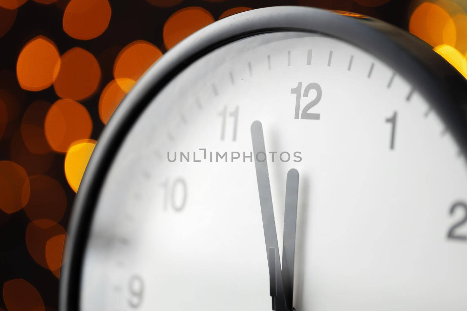ew Year eve concept with alarm clock against blurred garland background