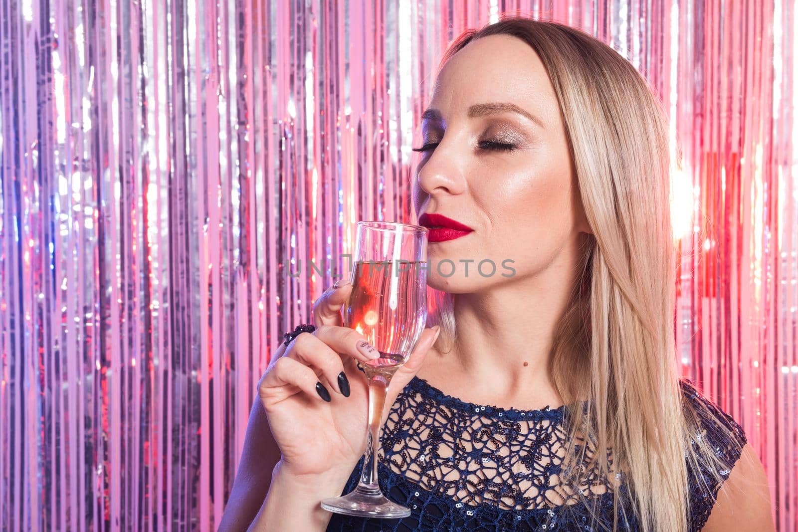 Party, drinks, holidays and celebration concept - smiling woman in evening dress with glass of sparkling wine over shiny background. by Satura86