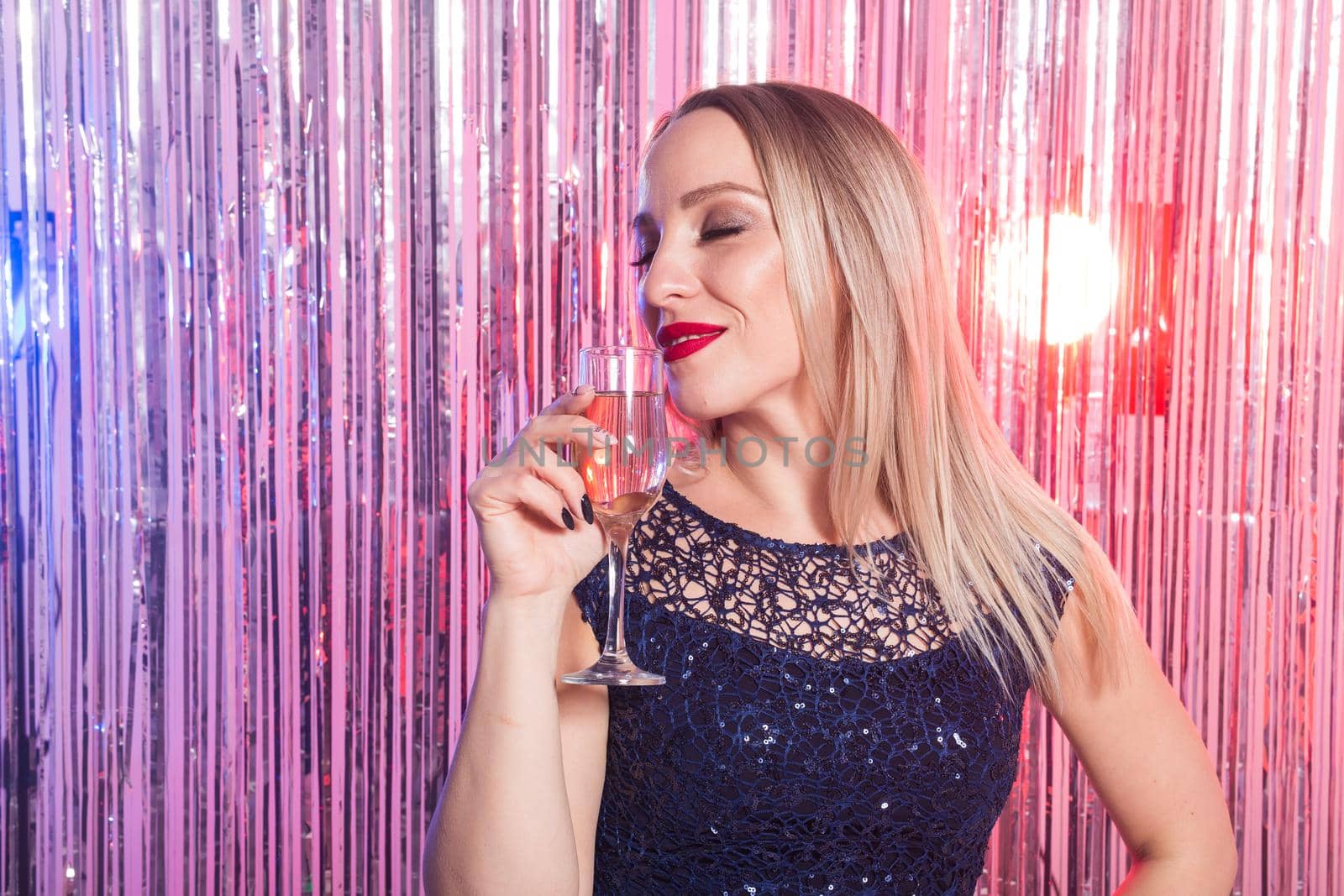 Party, drinks, holidays and celebration concept - smiling woman in evening dress with glass of sparkling wine over shiny background. by Satura86