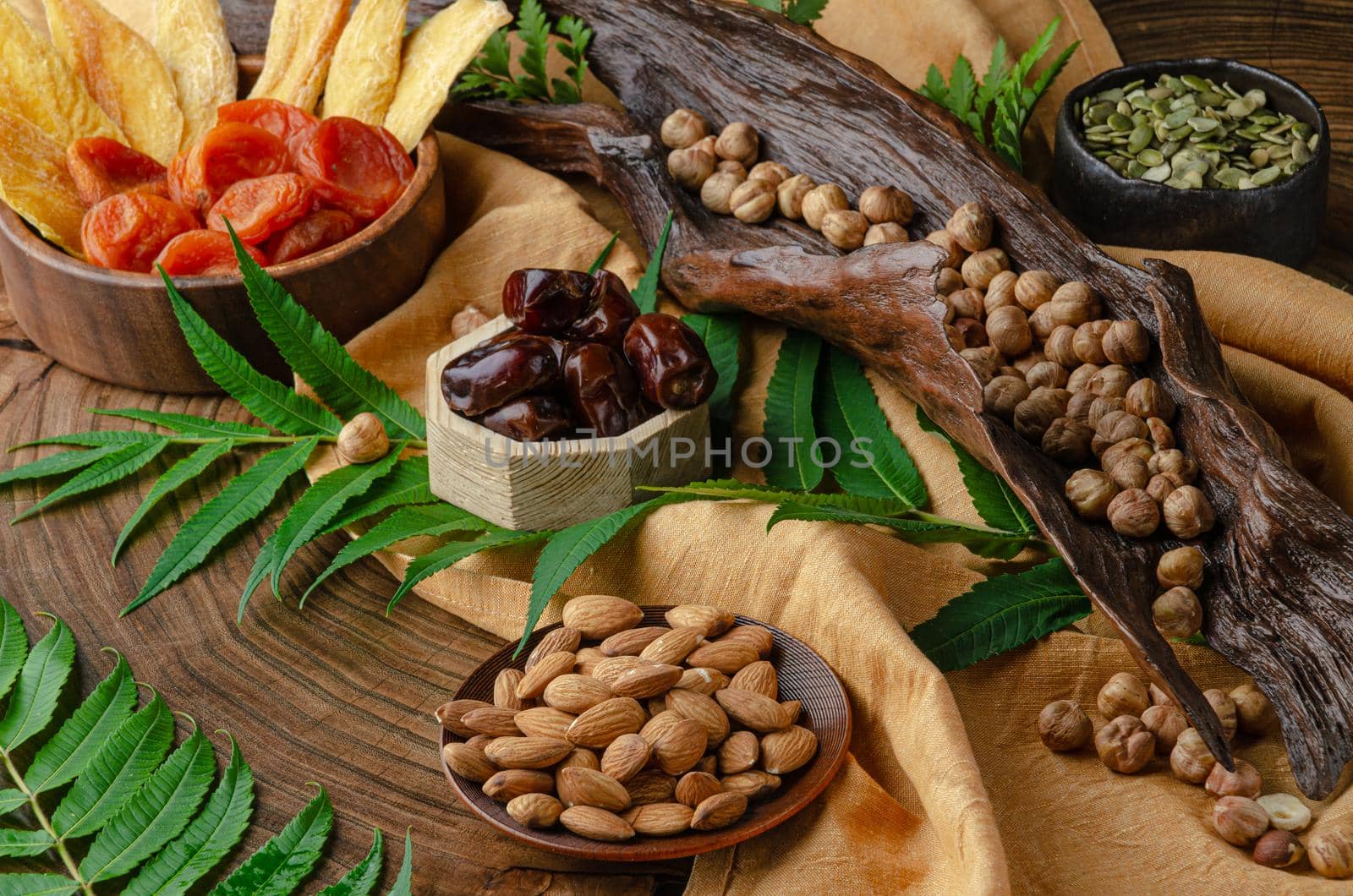 still life of nuts and dried fruits on a wooden table with fern leaves