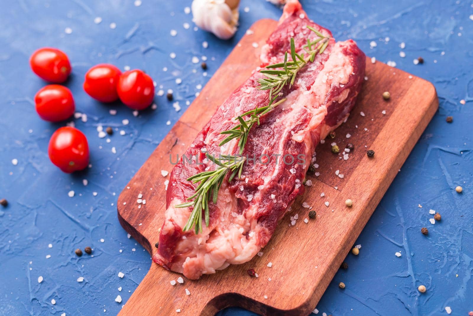 Fresh raw meat for steak on wooden cutting board, close-up. by Satura86