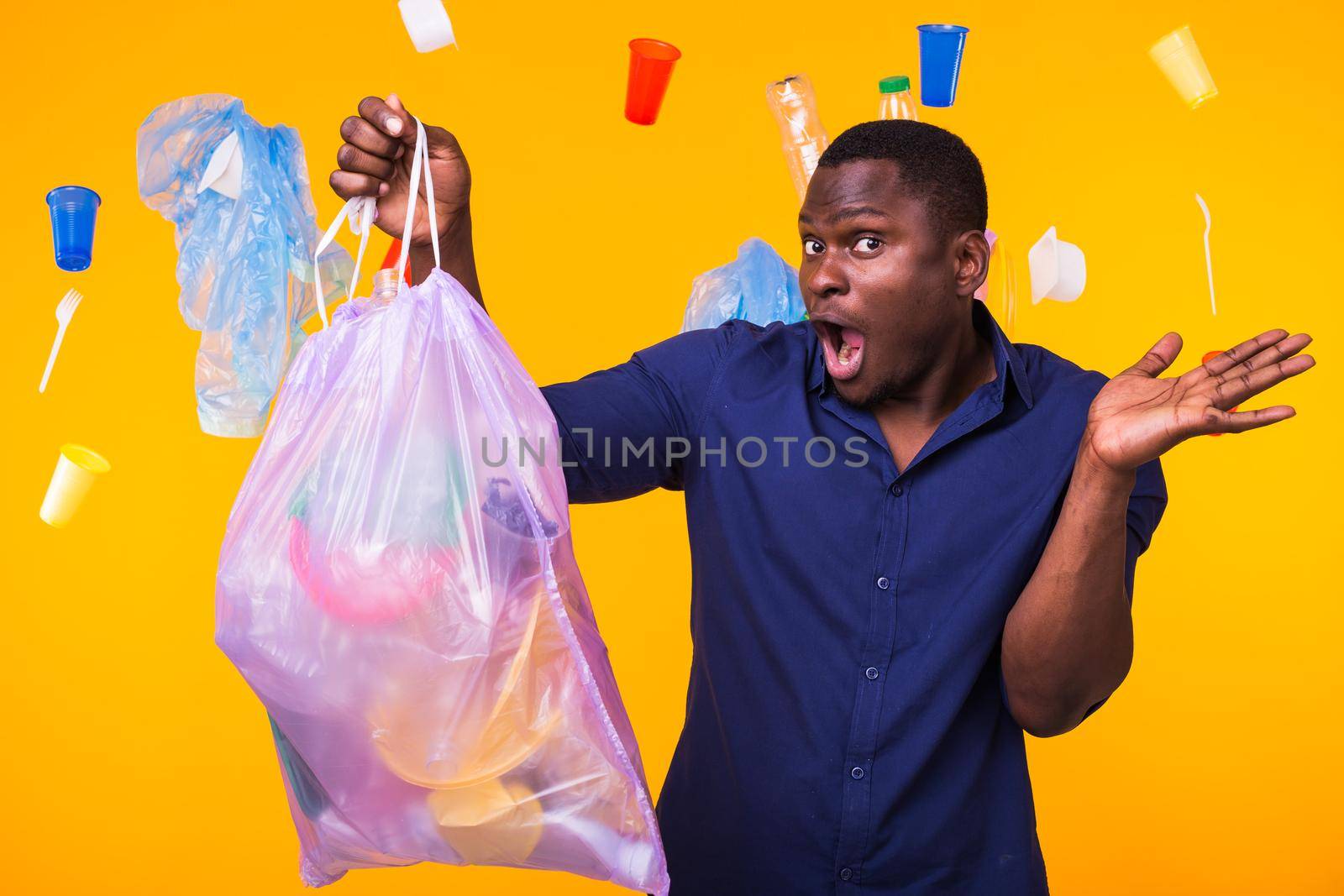 Problem of trash, plastic recycling, pollution and environmental concept - surprised man carrying garbage bag on yellow background by Satura86