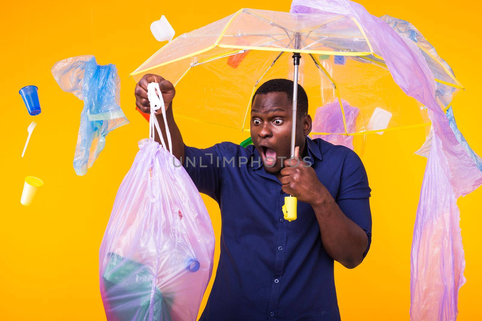 Problem of trash, plastic recycling, pollution and environmental concept - surprised man carrying garbage bag on yellow background by Satura86