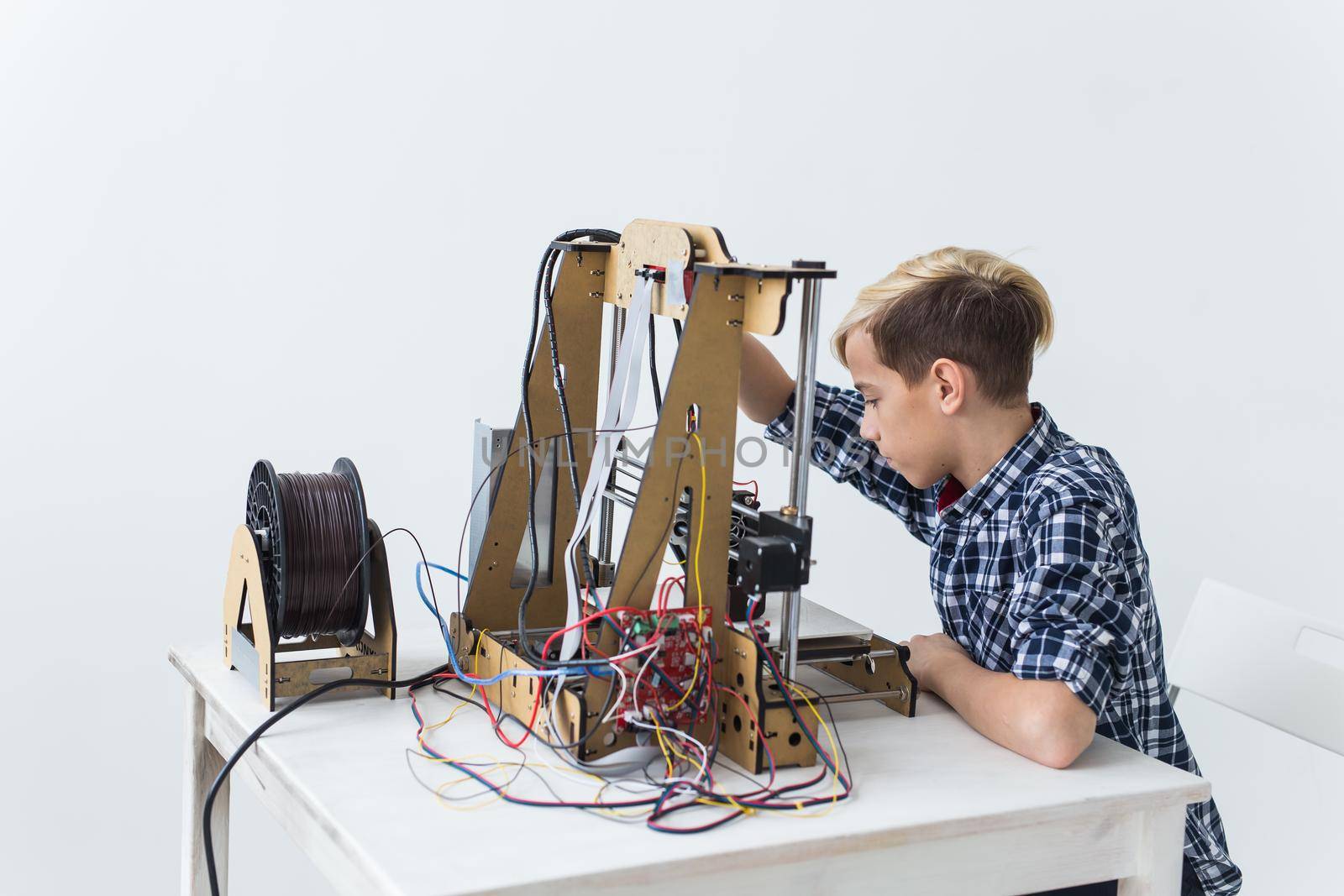 Education, children, technology concept - teen boy is printing on 3d printer