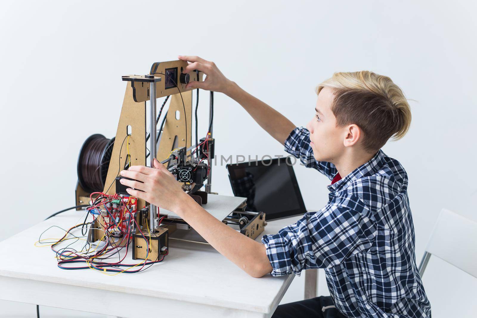 Education, children, technology concept - teen boy is printing on 3d printer