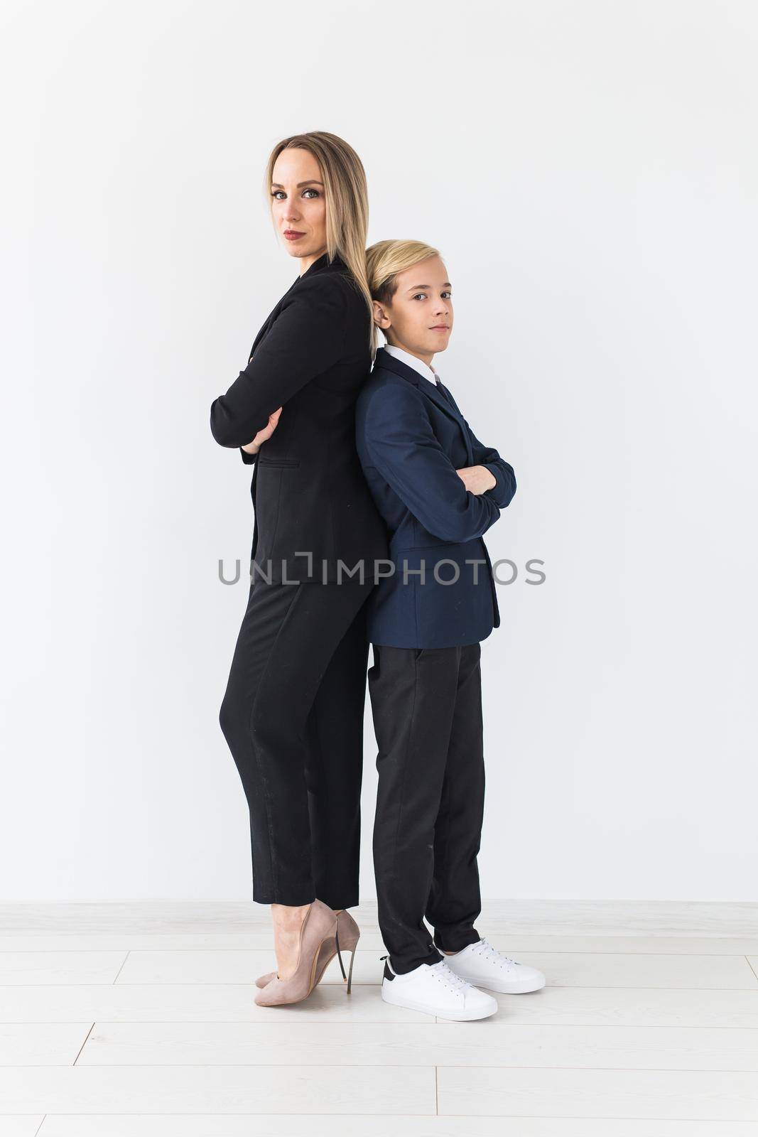 Teenager and single parent - Young mother and son standing together, back to back on white background. by Satura86