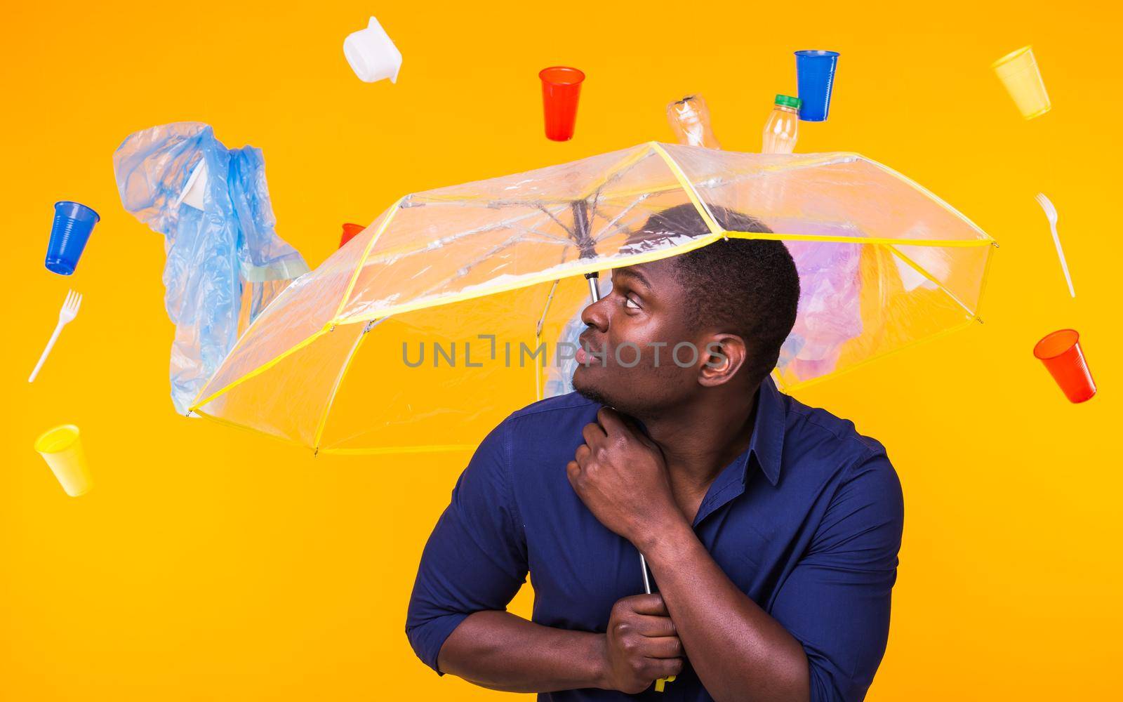 World Environment Day, plastic recycling problem and environmental disaster concept - Surprised african american man looking on trash on yellow background. by Satura86