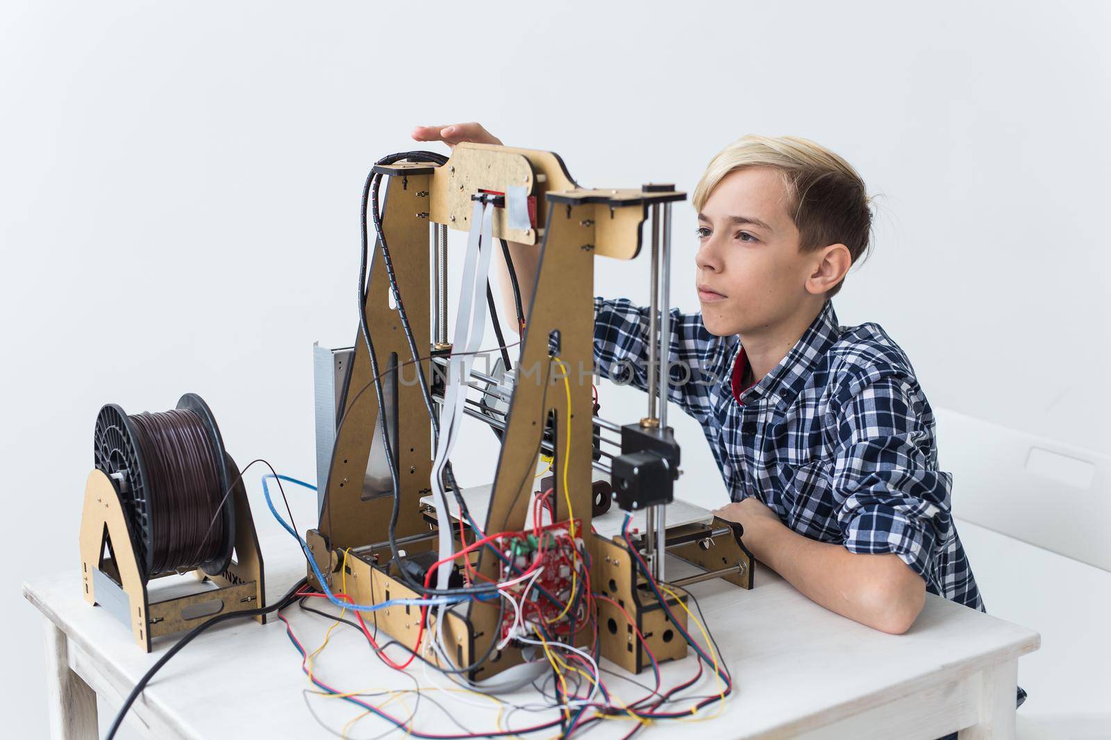 Education, children, technology concept - teen boy is printing on 3d printer. by Satura86