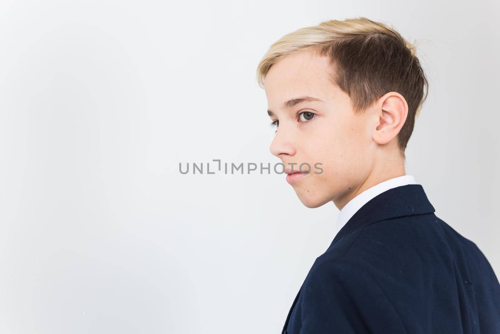 Portrait of stylish school boy teenager in white shirt and jacket against white background with copy space