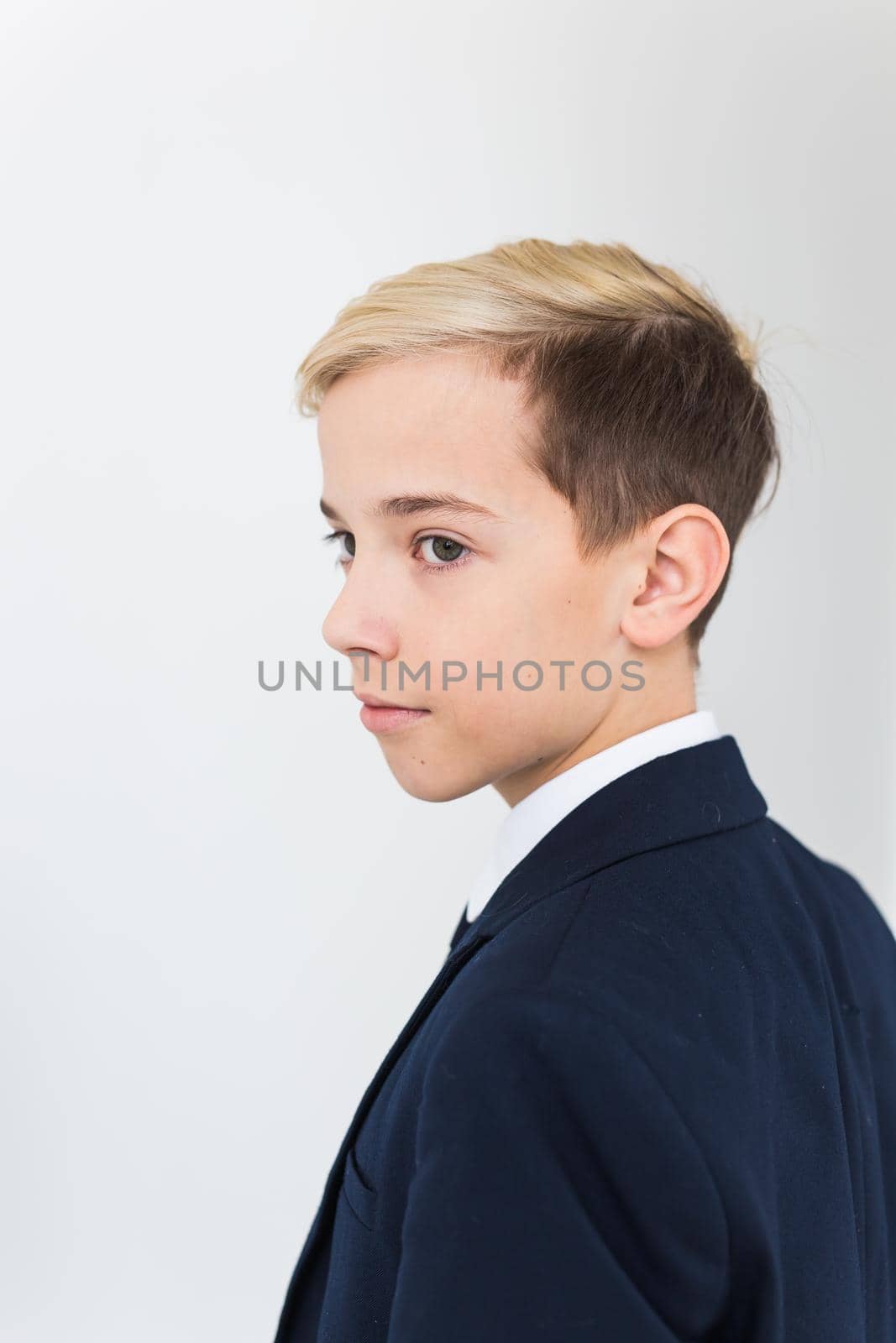 Portrait of stylish school boy teenager in white shirt and jacket against white background with copy space