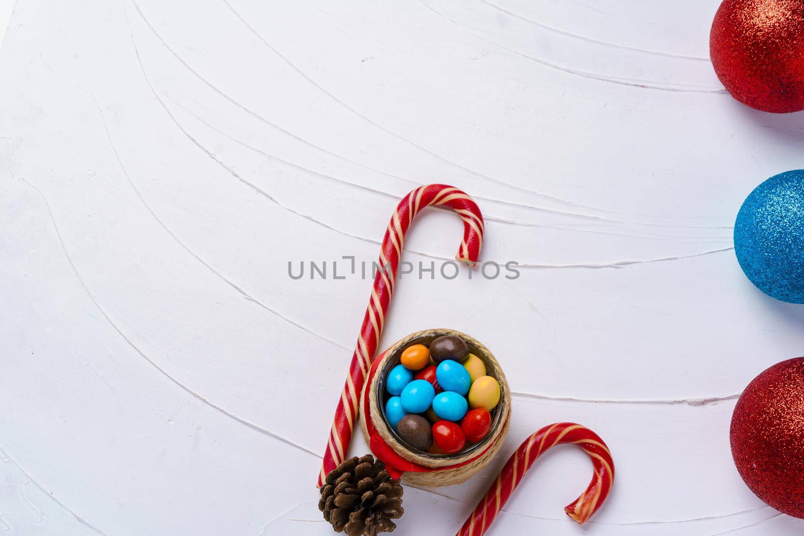 Festive background with candy canes and Christmas baubles on wooden board