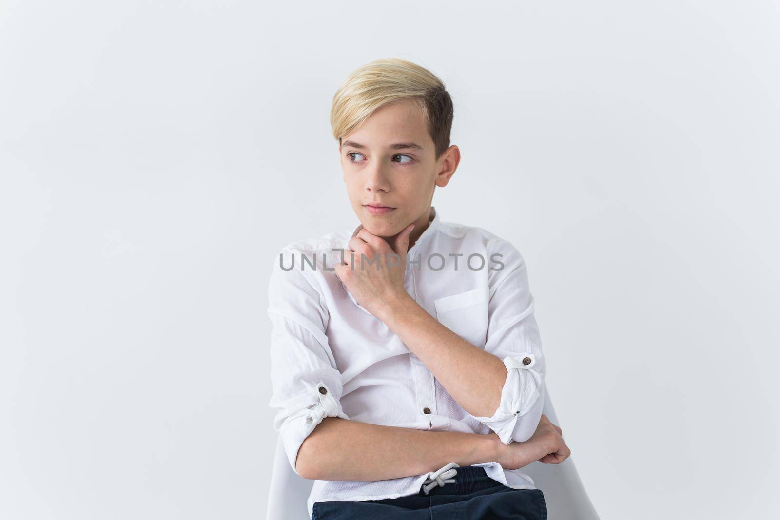 Solitude, loneliness and boredom concept - Bored teen student sitting in a school chair isolated on white background by Satura86