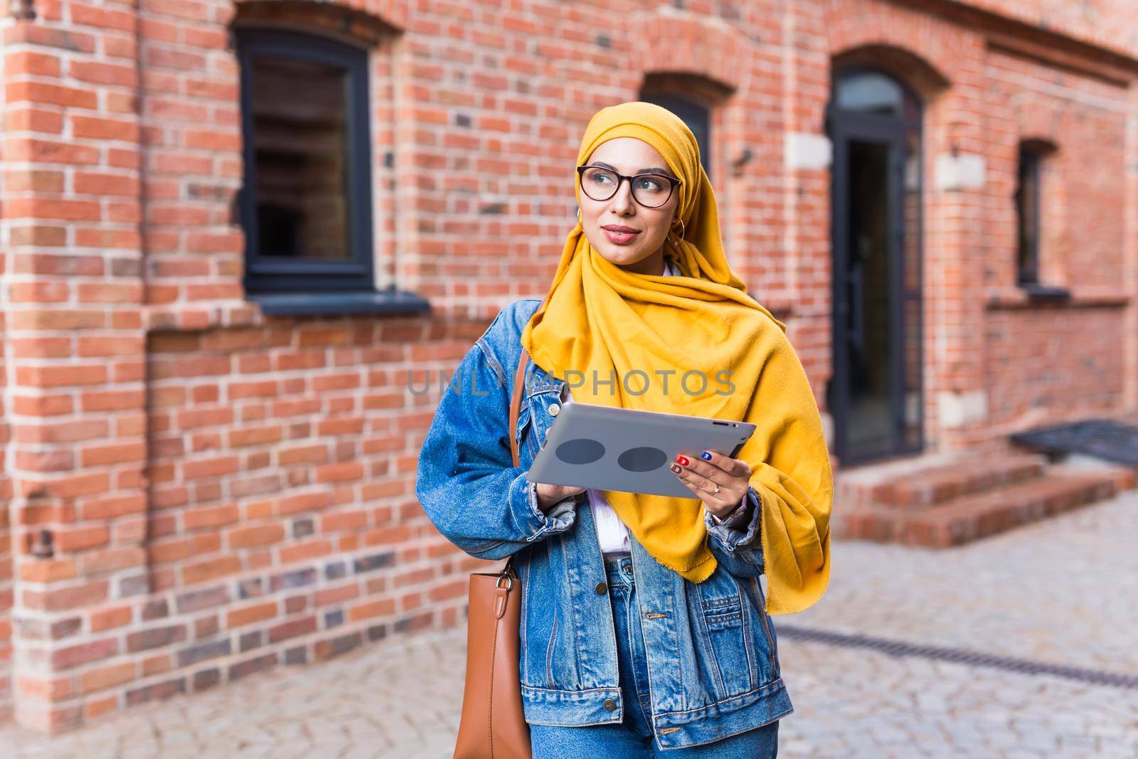 Arab woman student. Beautiful muslim female student wearing bright yellow hijab holding tablet. by Satura86