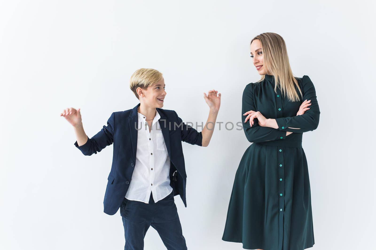 Teenager and single parent - Young mother and son dancing together on white background. by Satura86