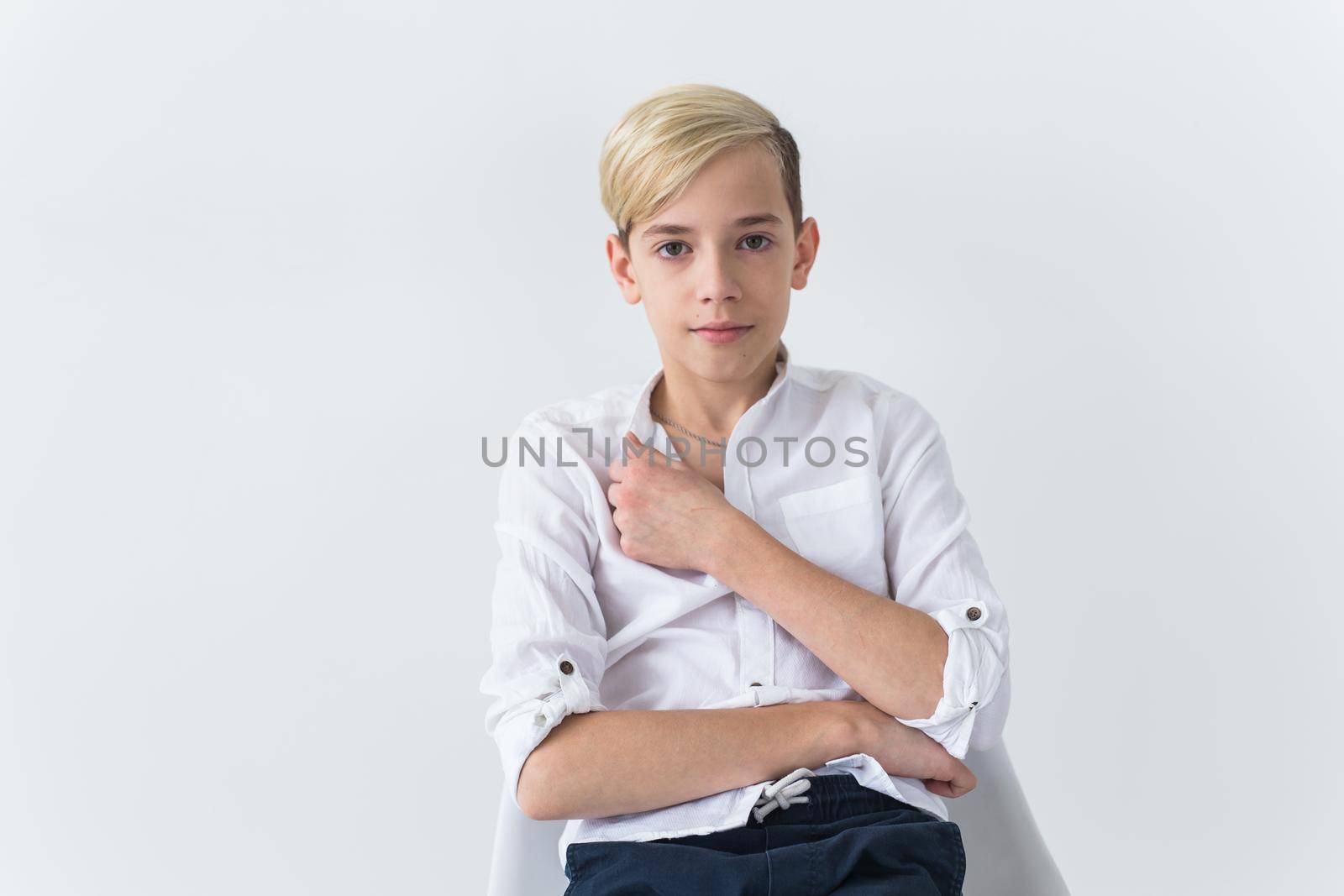 Solitude, loneliness and boredom concept - Bored teen student sitting in a school chair isolated on white background by Satura86