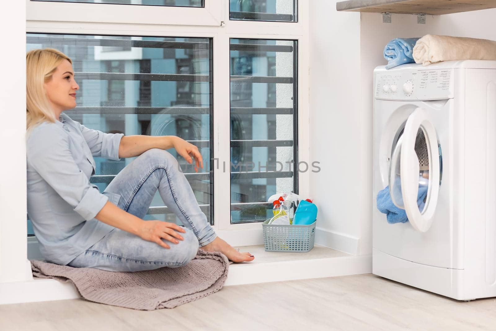 A young housewife with washing machine and clothes. Washing day.