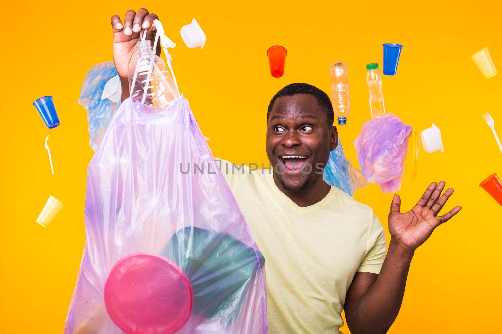 Problem of trash, plastic recycling, pollution and environmental concept - surprised man carrying garbage bag on yellow background.