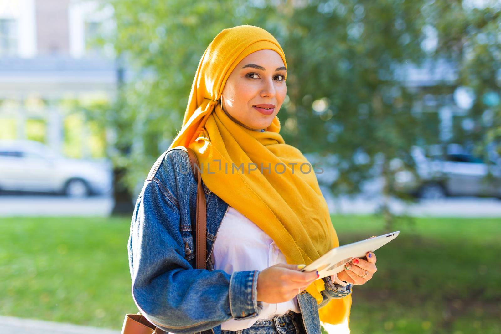 Arab woman student. Beautiful muslim female student wearing yellow hijab holding tablet