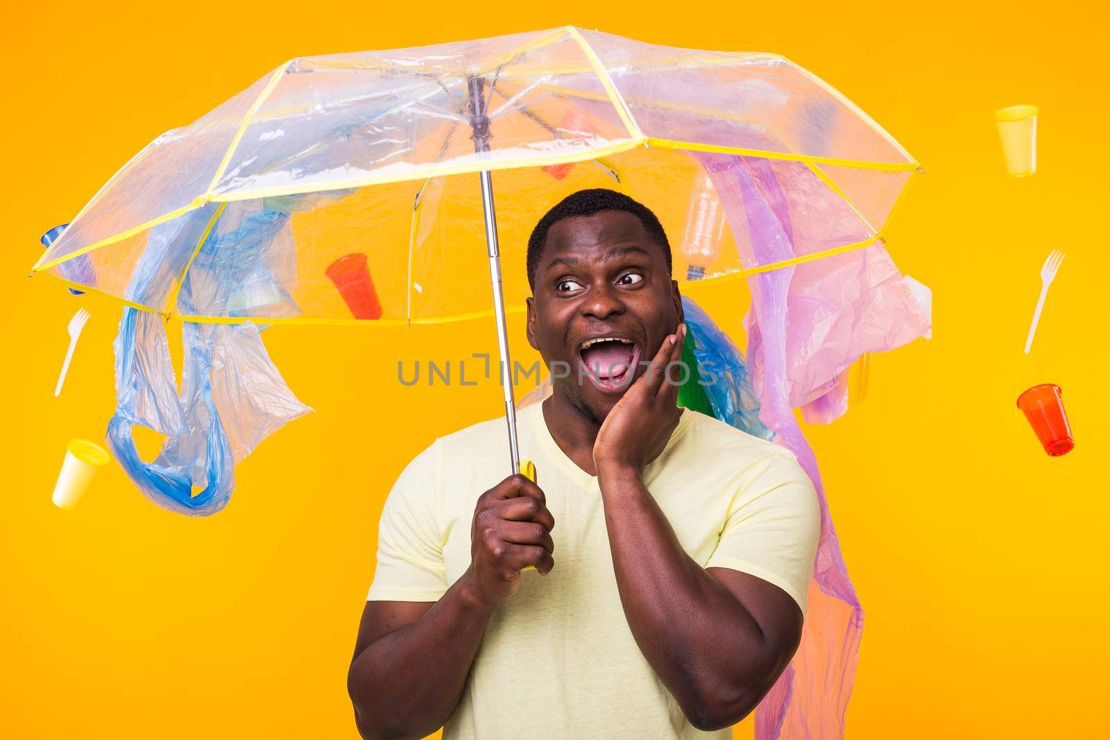 Plastic recycling problem, ecology and environmental disaster concept - Scared man screaming on yellow background with trash. He is worried about ecology disaster by Satura86