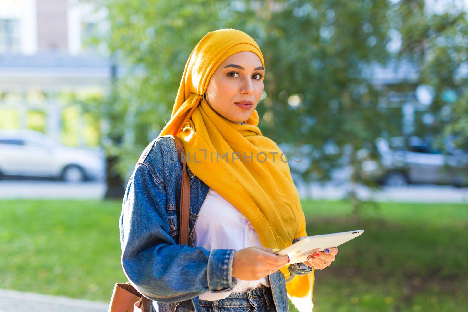 Arab woman student. Beautiful muslim female student wearing yellow hijab holding tablet