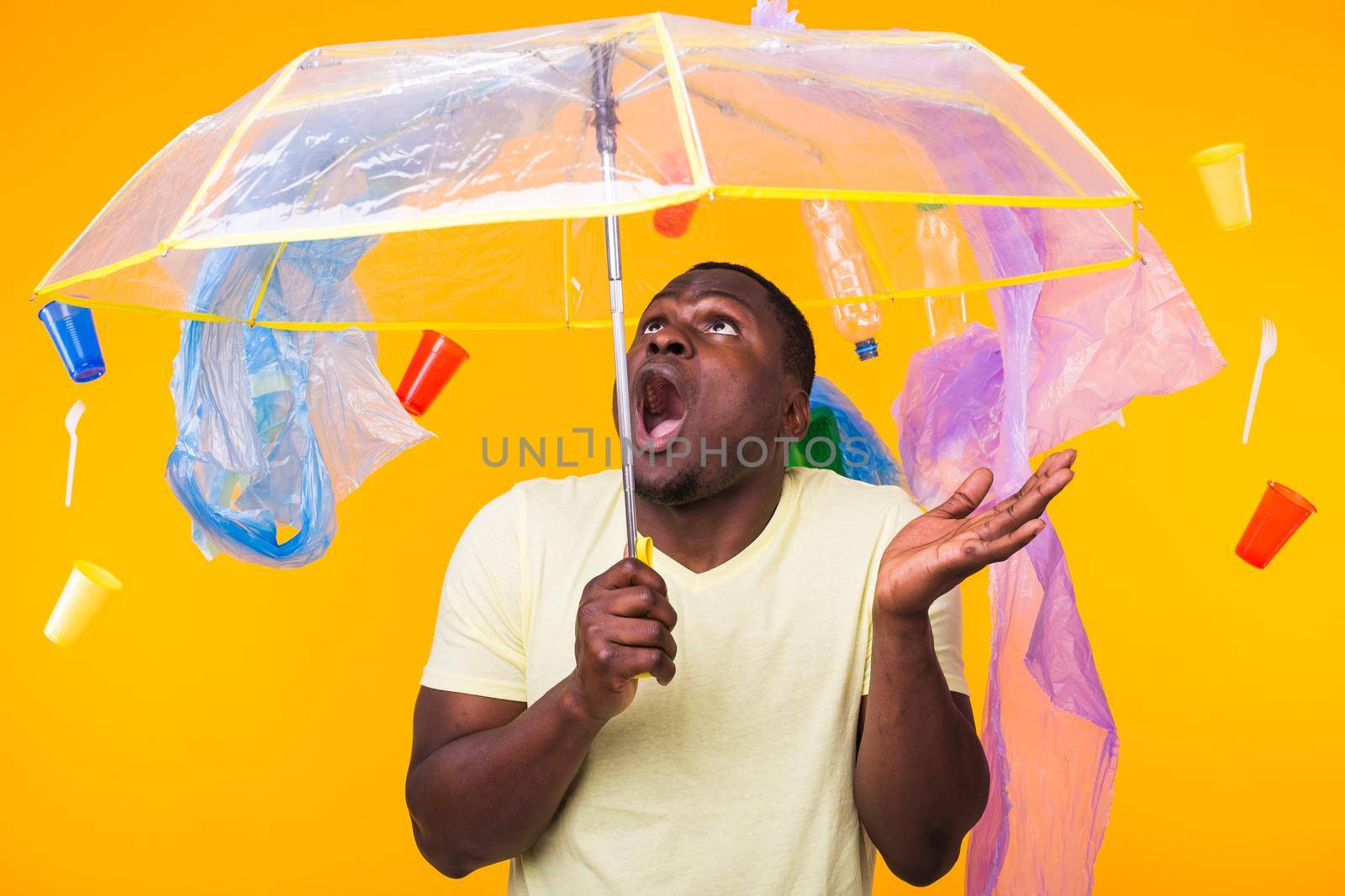 World Environment Day, plastic recycling problem and environmental disaster concept - Terrified man on yellow background with trash.