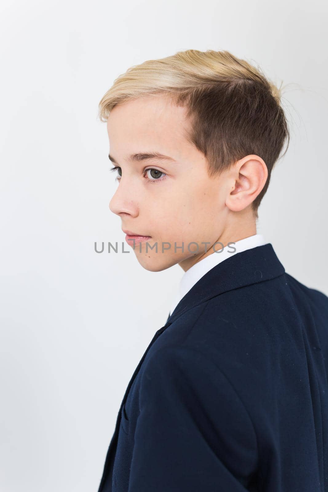 Portrait of stylish school boy teenager in white shirt and jacket against white background with copy space