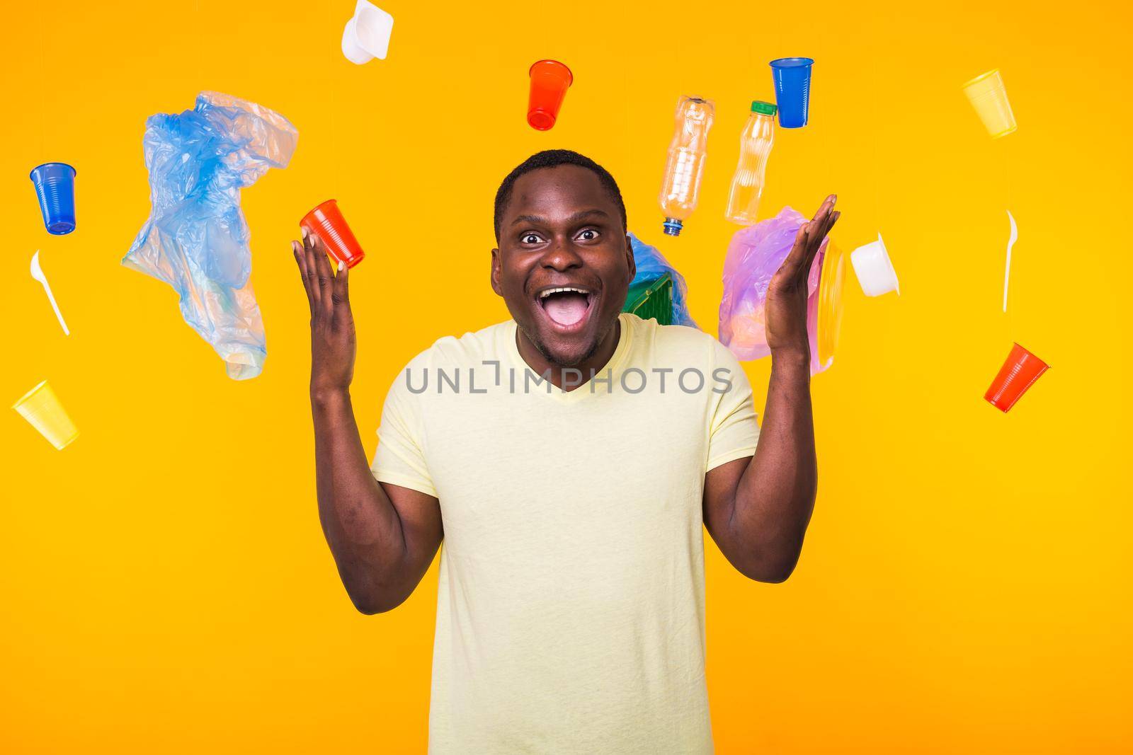Plastic recycling problem, ecology and environmental disaster concept - Scared man screaming on yellow background with trash. He is worried about ecology disaster by Satura86