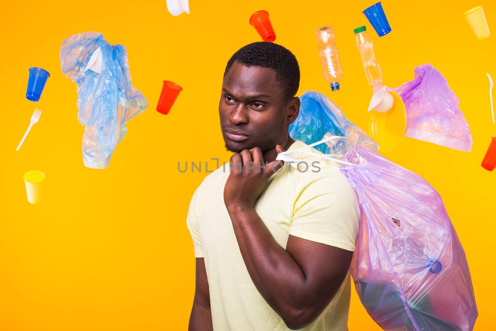 Problem of trash, plastic recycling, pollution and environmental concept - sad man holding garbage bag on yellow background by Satura86